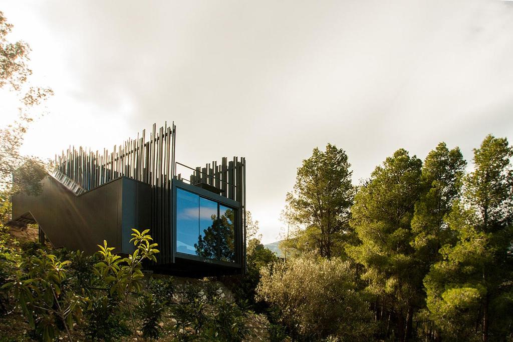 une maison en verre sur une colline avec des arbres dans l'établissement VIVOOD Landscape Hotel & Spa - Designed for Adults, à Benimantell