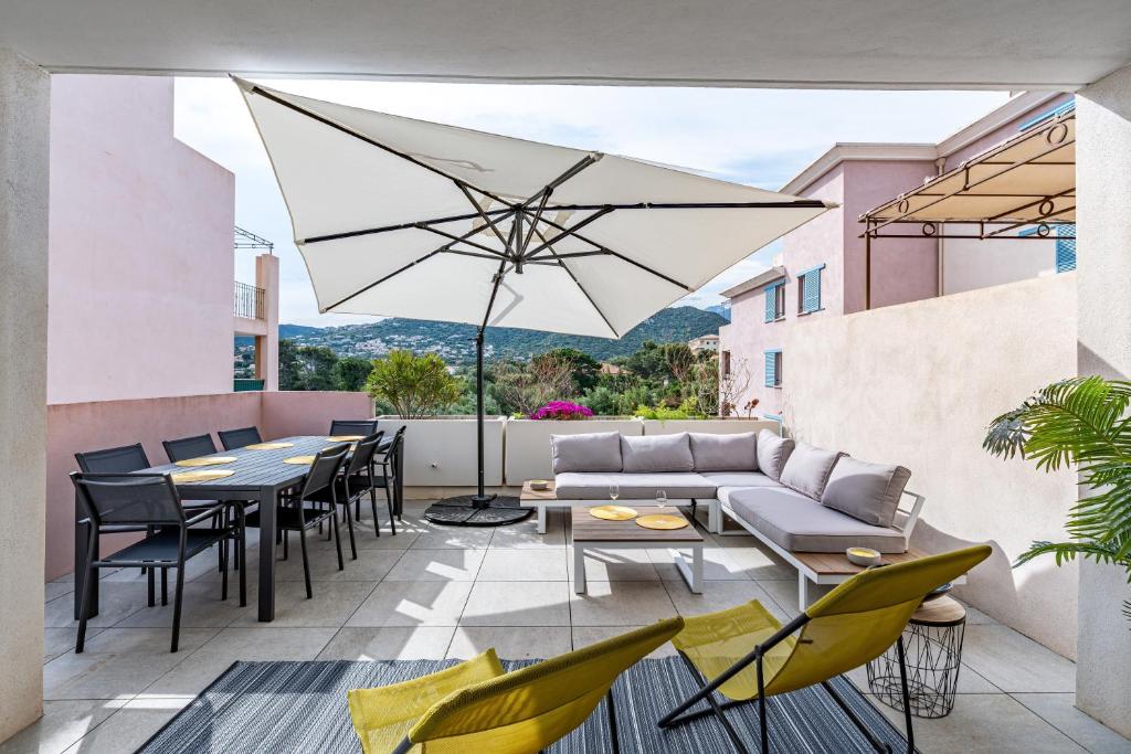 un patio avec tables, chaises et un parasol dans l'établissement Paoli, à LʼÎle-Rousse