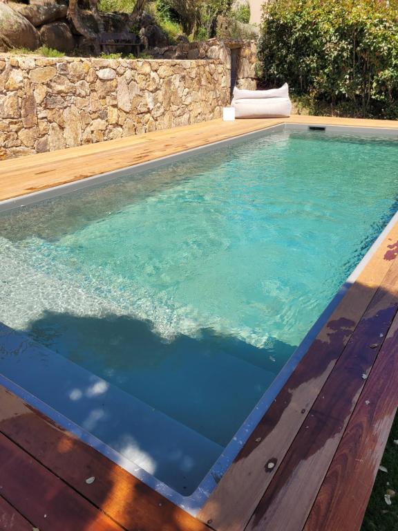a swimming pool with blue water and a wooden deck at Bel appartement dans hameau calme in Bonifacio