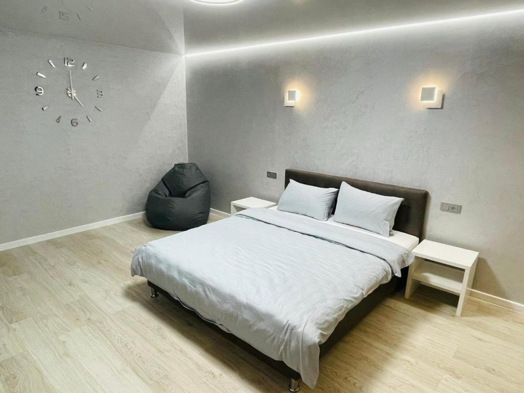 1 dormitorio con 1 cama y reloj en la pared en Апартаменты VIP в центре города. Гагарина 39, en Krivoy Rog