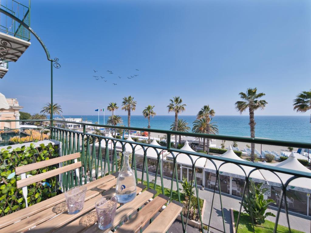 a table on a balcony with the ocean in the background at Medusa Apartment - Lungomare in Finale Ligure