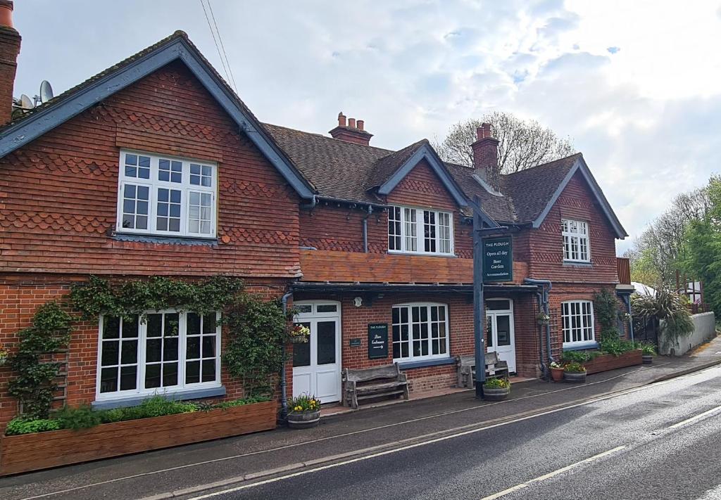 a red brick house with white windows on a street at The Plough Itchen Abbas in Winchester