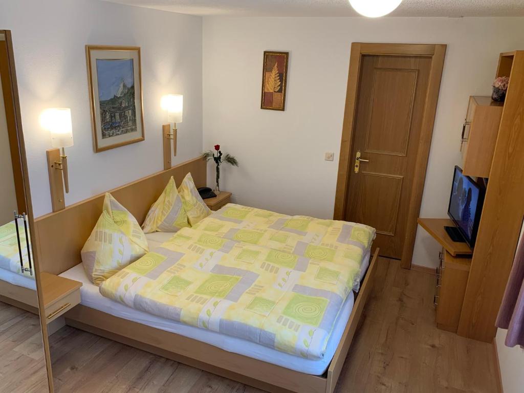 a bedroom with a large bed with a yellow comforter at Alpenblick in Zermatt