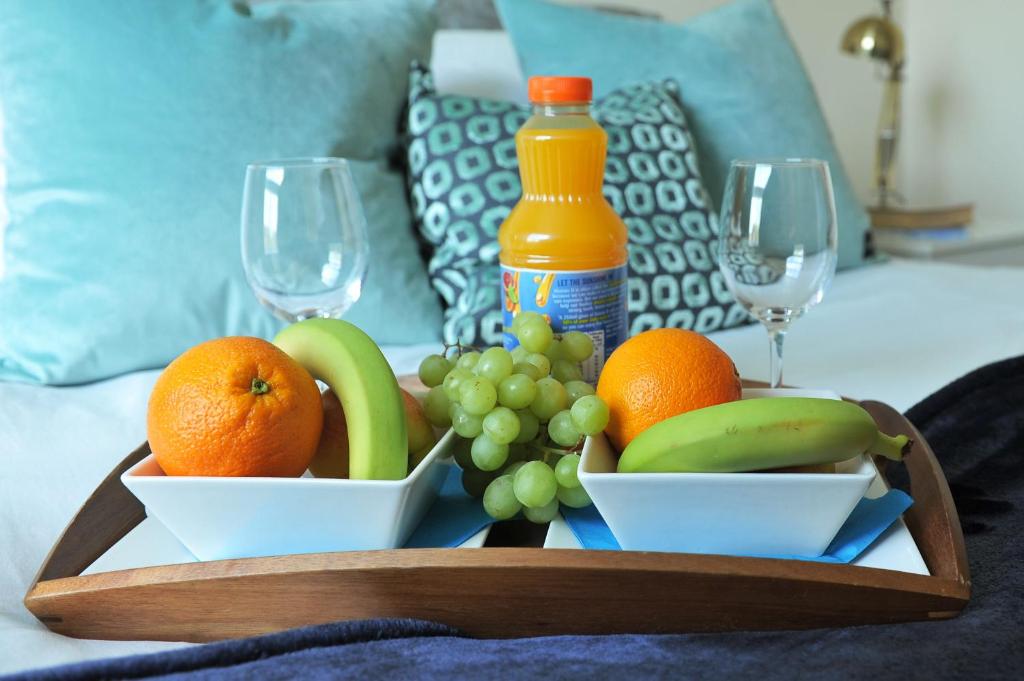 a tray with fruit and wine glasses on a bed at Hunters Wharf River View by Select SA in Reading