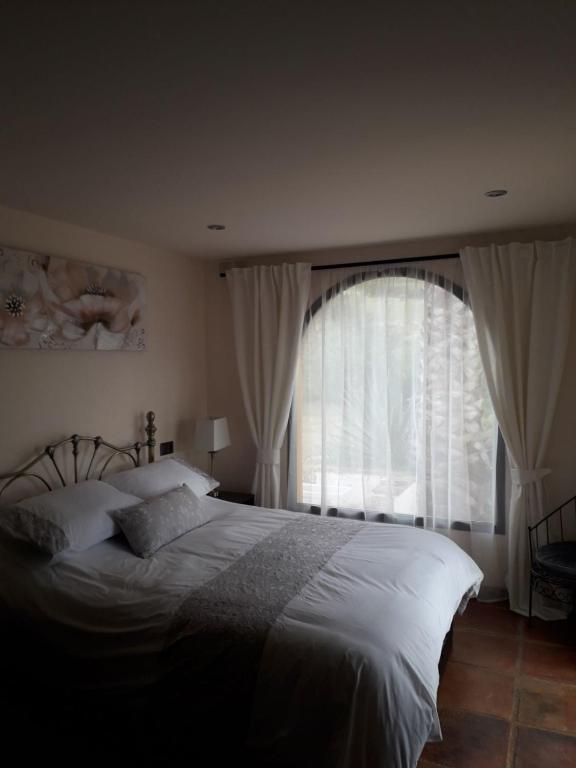 sypialnia z łóżkiem i dużym oknem w obiekcie Casita Blanco w Maladze