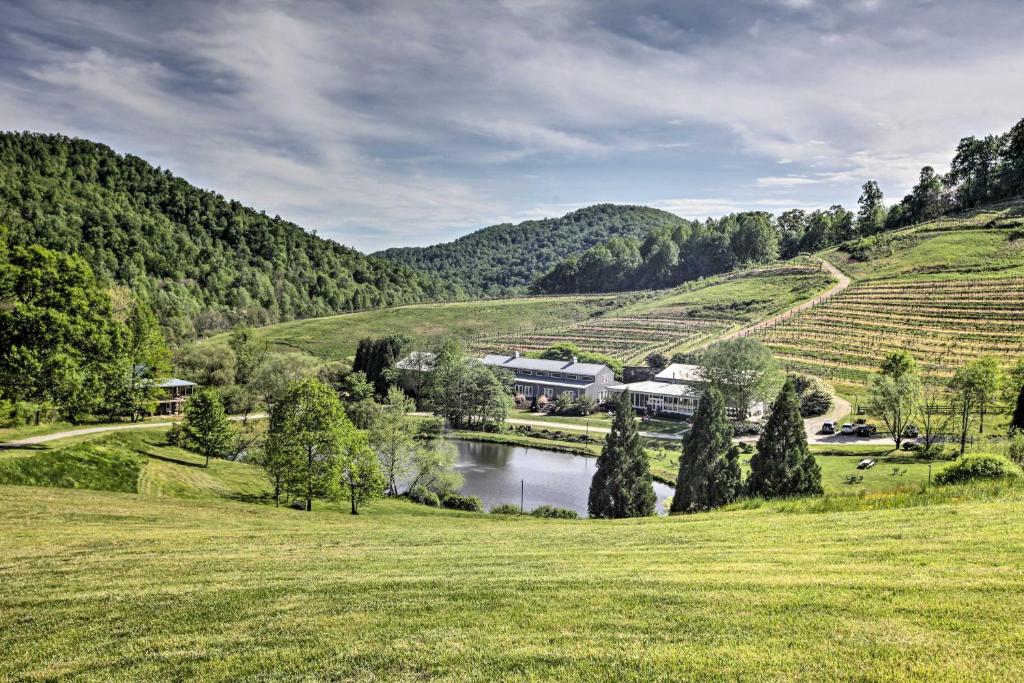una granja en medio de un campo con un río en Romantic Log Cabin Escape on Delfosse Winery! en Faber