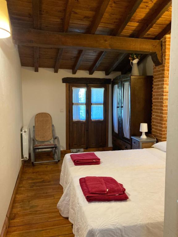 Casa rural Adelaida في Villanueva del Conde: غرفة نوم بسرير وفوط حمراء عليها
