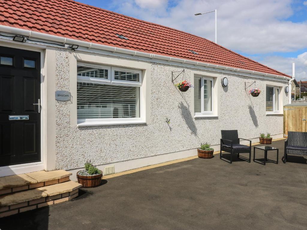 a white house with a black door and a patio at Seascape in Burntisland