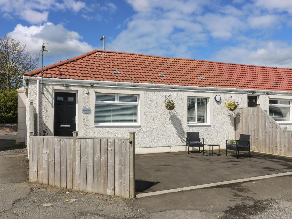 a white house with a fence and two chairs at Shore View in Burntisland