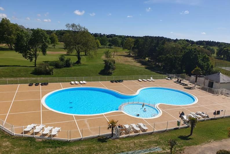 einen Blick über einen großen Pool mit Stühlen in der Unterkunft Madame Vacances Les Maisons de Fontenelles in LʼAiguillon-sur-Vie