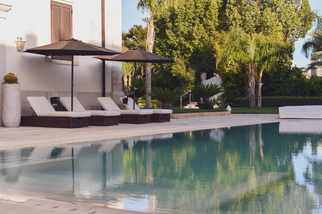 una piscina con sedie e ombrelloni accanto a una casa di Relais Villa Magnolia a Conversano