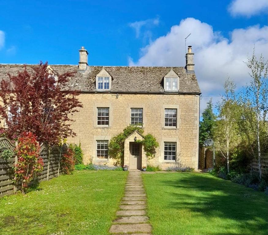 an old brick house with a grass yard at Darly Cottage in Bourton on the Water