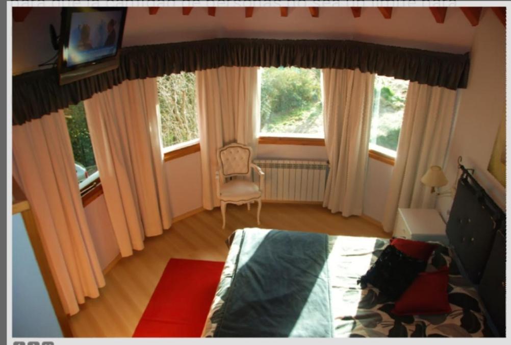a bedroom with a bed and a chair and windows at Bungalows Maniu in San Carlos de Bariloche