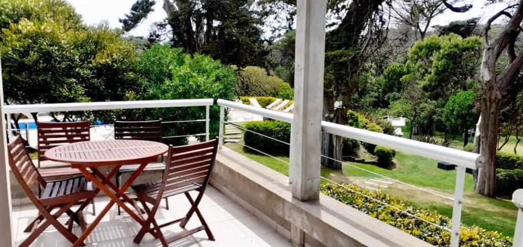 a table and chairs on a balcony with a view of a garden at Villa Agostina Apart & Spa in Mar de las Pampas