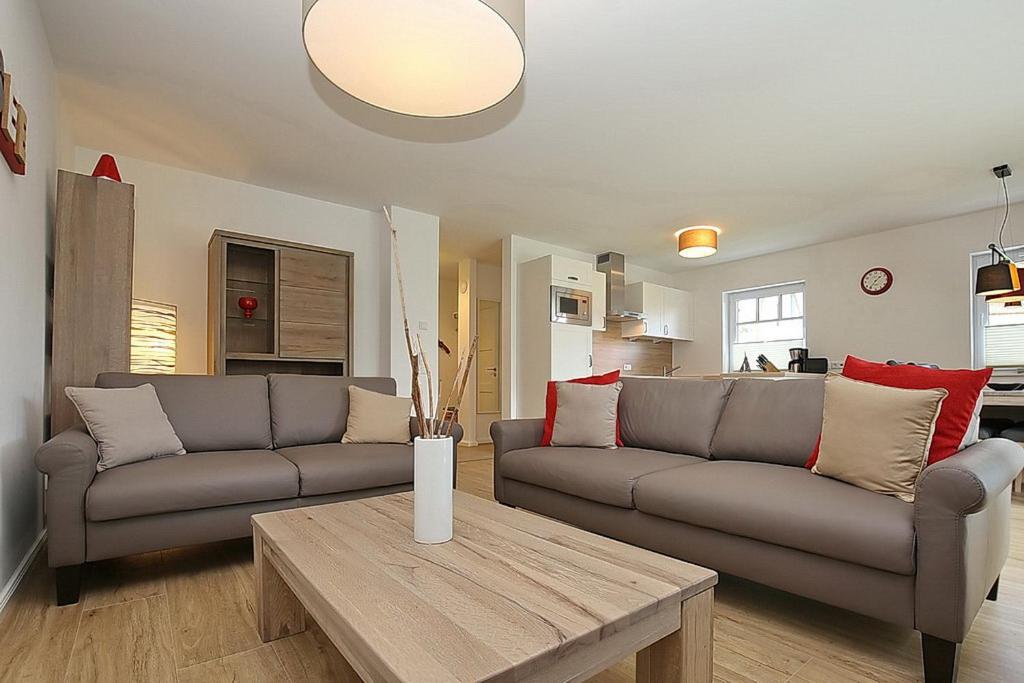 a living room with two couches and a table at Reethaus Am Mariannenweg 12b in Boltenhagen