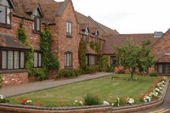une grande maison en briques avec un jardin en face de celle-ci dans l'établissement The Pear Tree Inn & Country Hotel, à Worcester