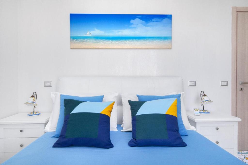 Schlafzimmer mit einem Bett mit blauer Bettwäsche und Kissen in der Unterkunft Millie Sorrento Suites in Sorrent