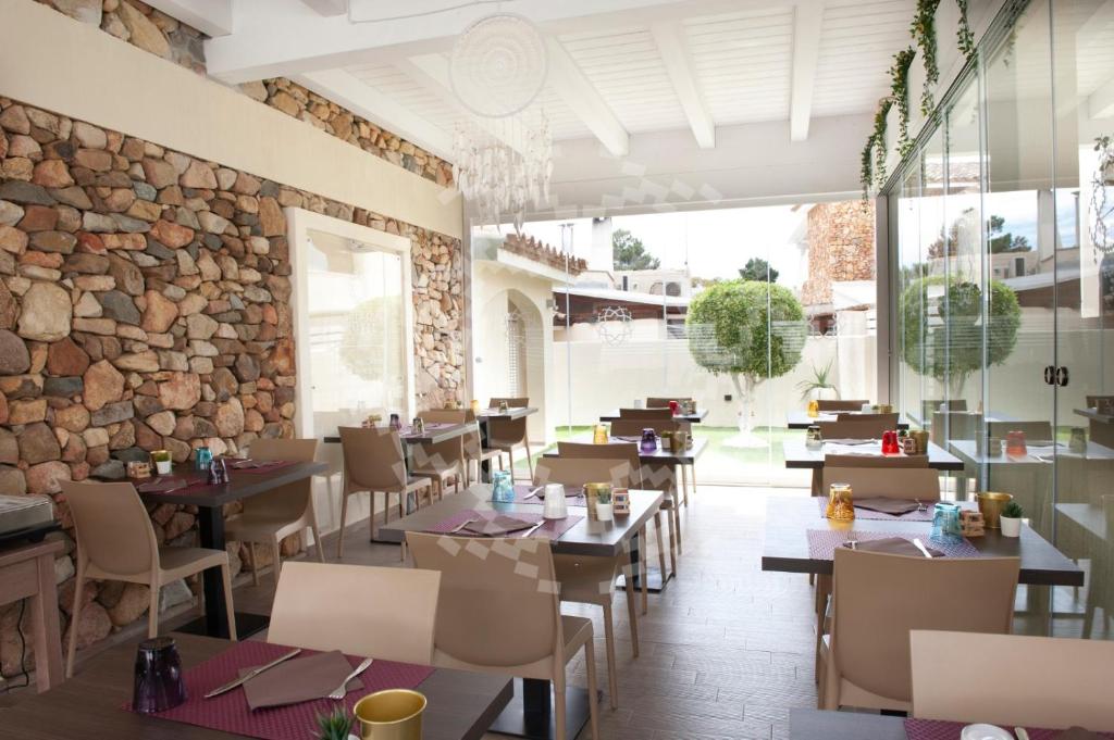 a restaurant with tables and chairs and a stone wall at Suimi's Hotel in Villasimius