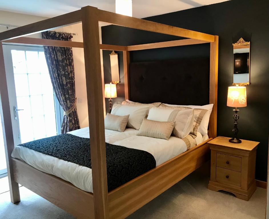 a bedroom with a wooden canopy bed with white pillows at Lindfields in Inverness