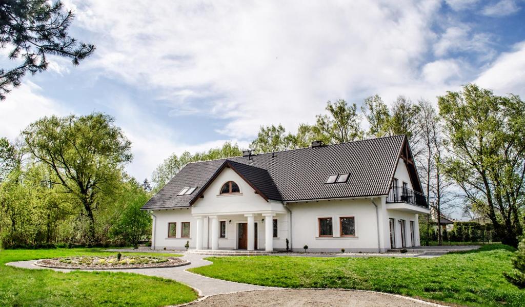a white house with a black roof at Dworek Polanica in Polanica-Zdrój