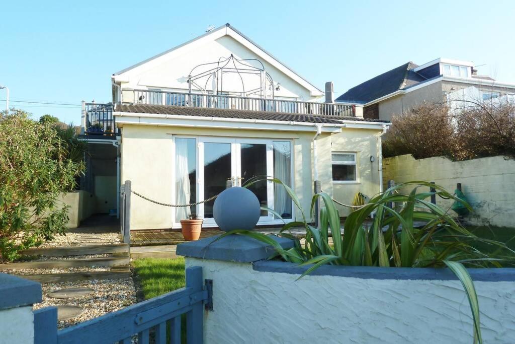 a house with a blue fence and a house at Stylish apartment - 2 min walk from Ogmore by sea beach with private garden, sea views & stunning sunsets, dog friendly in Tythegston