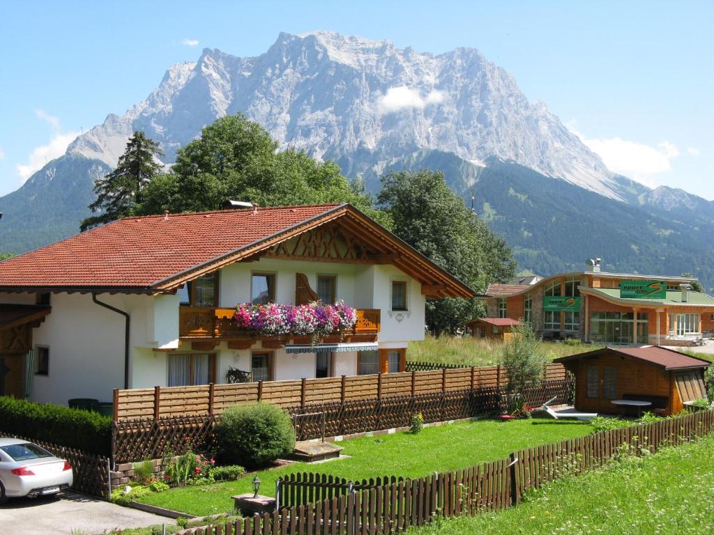a house with a fence in front of a mountain at Appartements Schneezauber in Lermoos