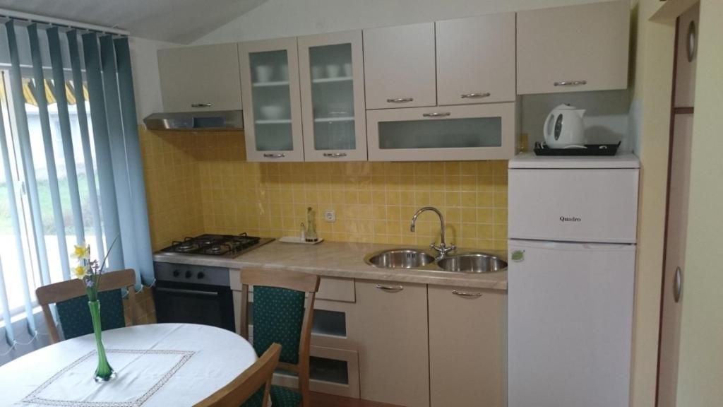 a kitchen with white cabinets and a table and a sink at Holiday house near the see in Luka