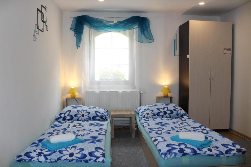 two beds in a small room with a window at Villa LIKE "garden-grill" in Bardejov