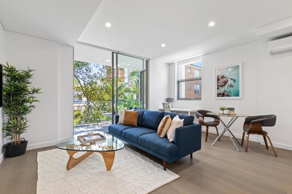 雪梨的住宿－Azure Apartments by Urban Rest，客厅配有蓝色的沙发和桌子