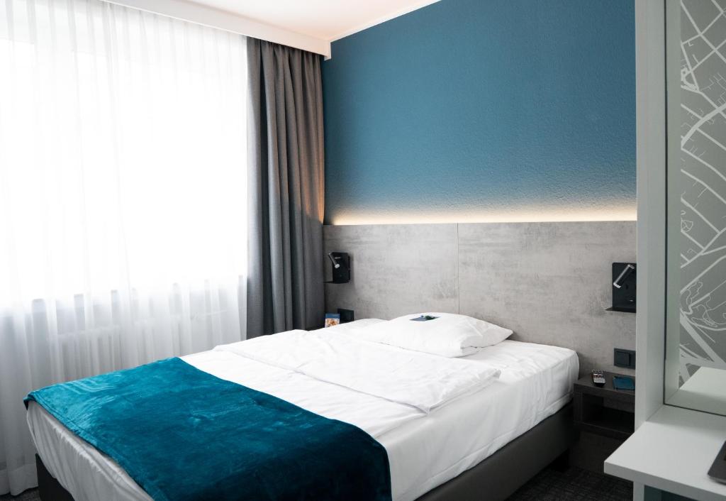 a bedroom with a bed with a blue wall at Comfort Garni Stadtzentrum Hotel in Bielefeld