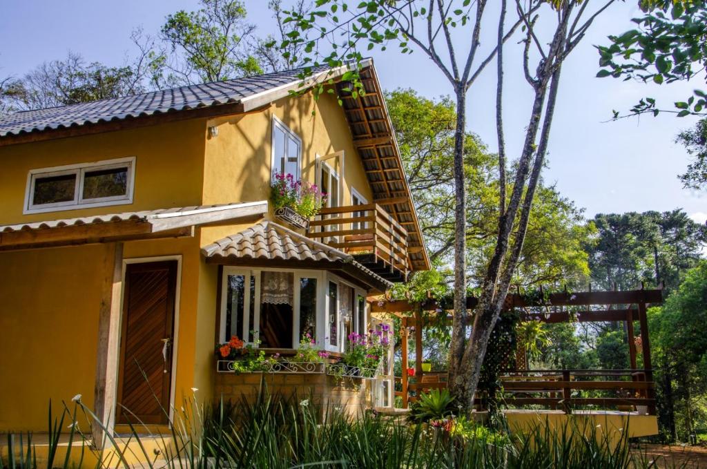 żółty dom z balkonem i kwiatami w obiekcie Casa De Férias e Hospedagem Ana Lua w mieście Visconde De Maua