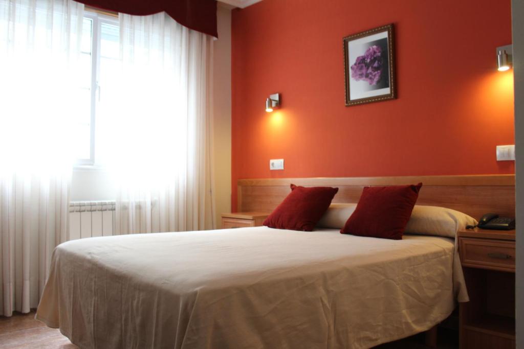 a bedroom with orange walls and a bed with red pillows at Hotel Rego Foz in Foz