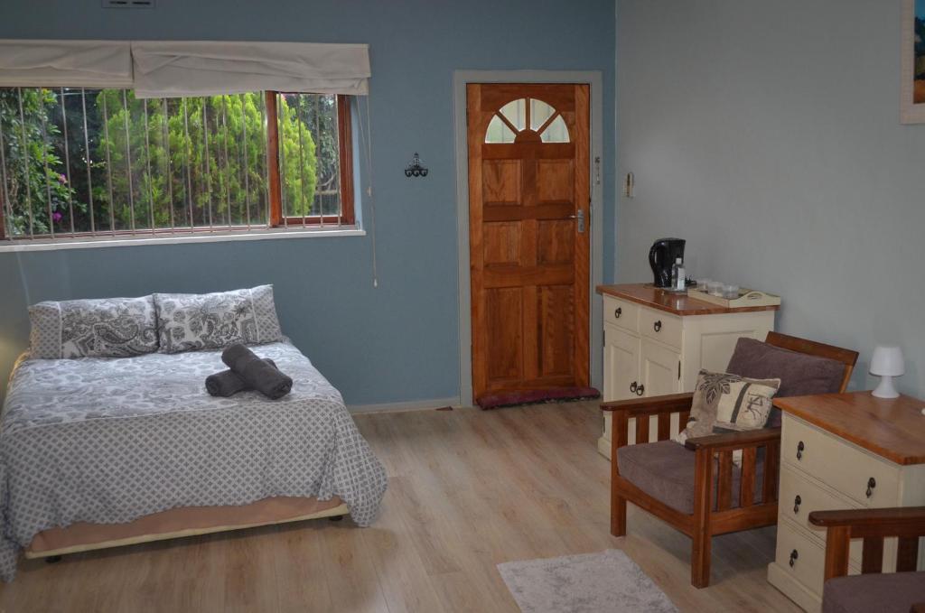1 dormitorio con 1 cama, 1 silla y 1 puerta en Seaforth Beach Apartment, en Ciudad del Cabo
