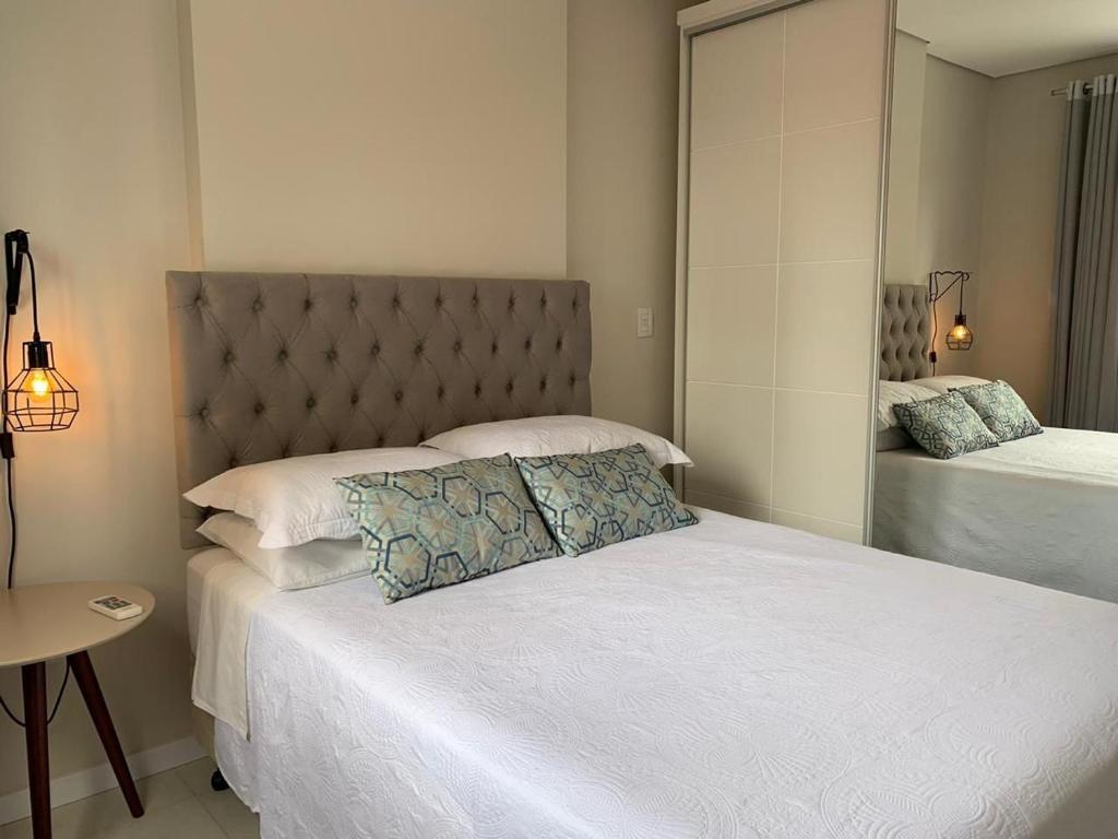 a bedroom with a large white bed with a headboard at Suíte Master Collection in Passo Fundo