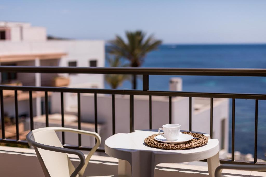 a table and a chair on a balcony with the beach at Apartamentos Bossa Bay - MC Apartamentos Ibiza in Ibiza Town