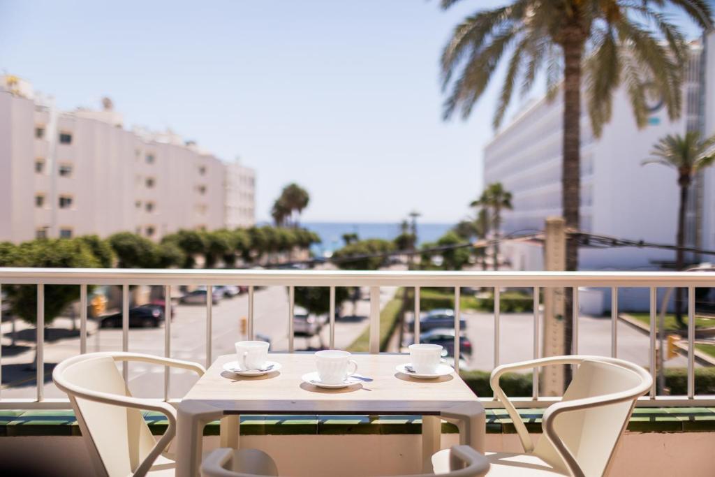 a white table with two cups and chairs on a balcony at Vistamar I - MC Apartments Ibiza in Playa d'en Bossa