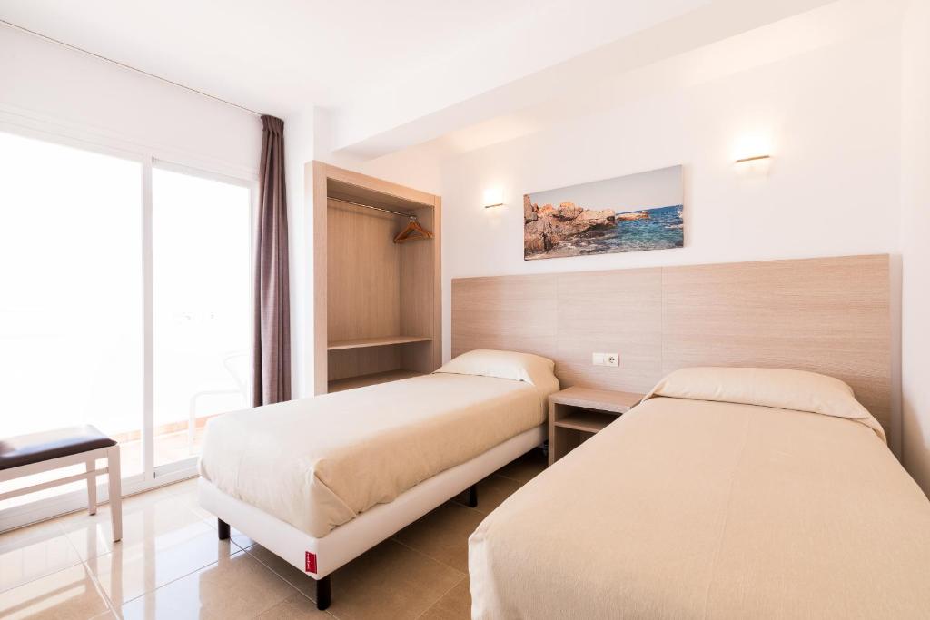 a hotel room with two beds and a window at Apartamentos Malacosta - MC Apartamentos Ibiza in Ibiza Town