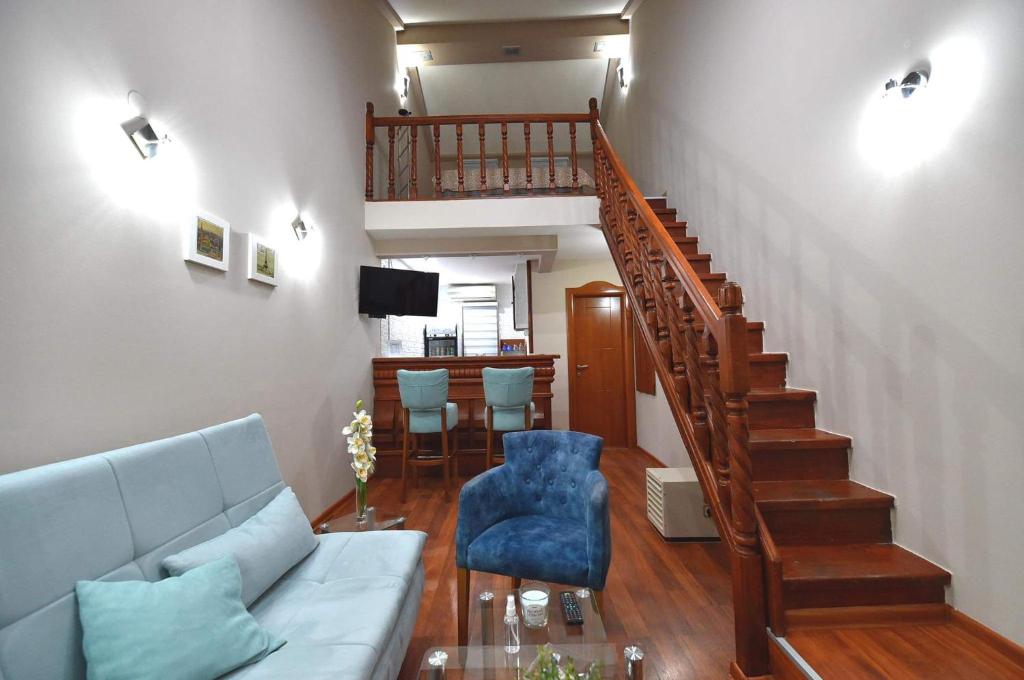 - un salon avec un canapé bleu et un escalier dans l'établissement Apartman Royal, à Gornji Milanovac