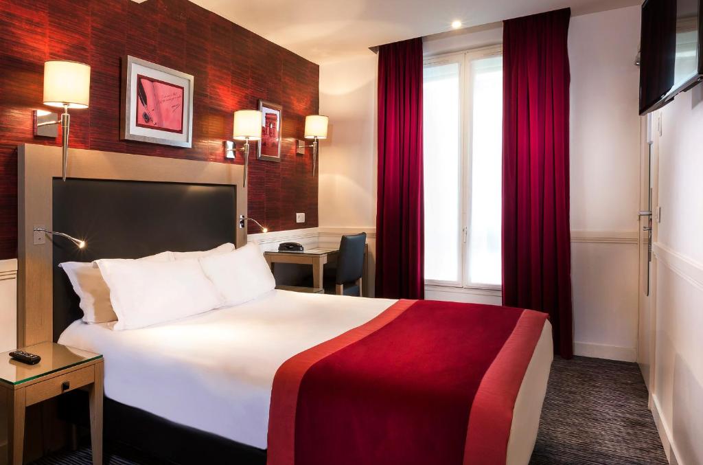 パリにあるホテル エリゼ フロベールの大きなベッドとデスクが備わるホテルルームです。