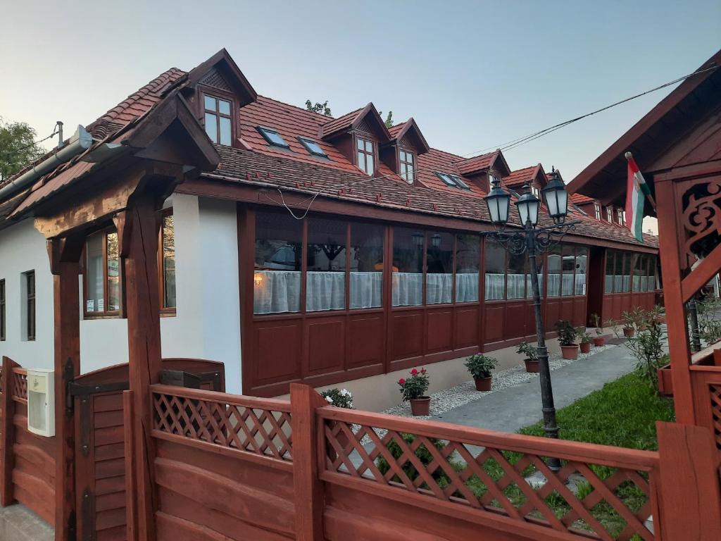 a house with a wooden fence and a porch at Hat Testvér Fogadó in Dömsöd