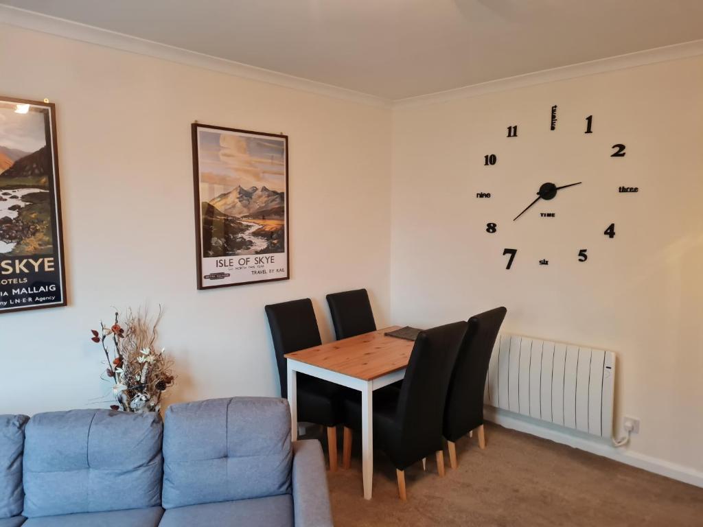 a dining room with a table and a clock on the wall at Modern Spacious Central Apartment in Portree