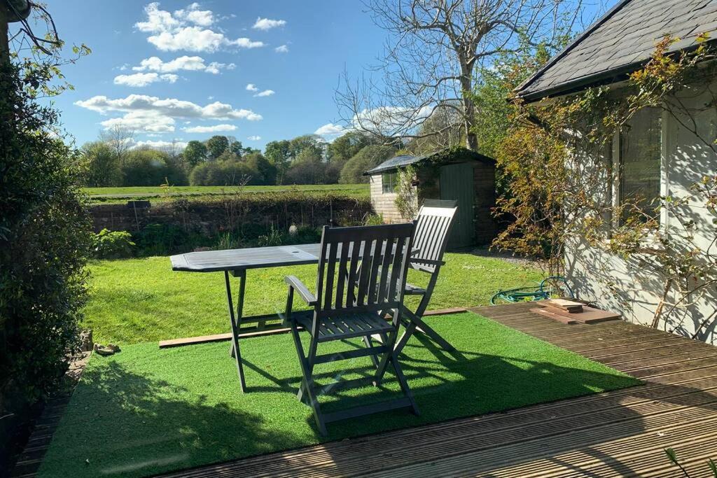 een bank naast een tafel in een tuin bij Spacious with spectacular views and private garden in Buxton