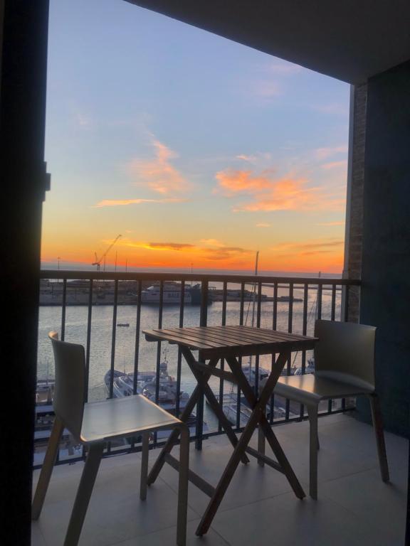 einen Tisch und Stühle auf einem Balkon mit Blick auf den Sonnenuntergang in der Unterkunft Harbour Views Puerto Denia II in Denia