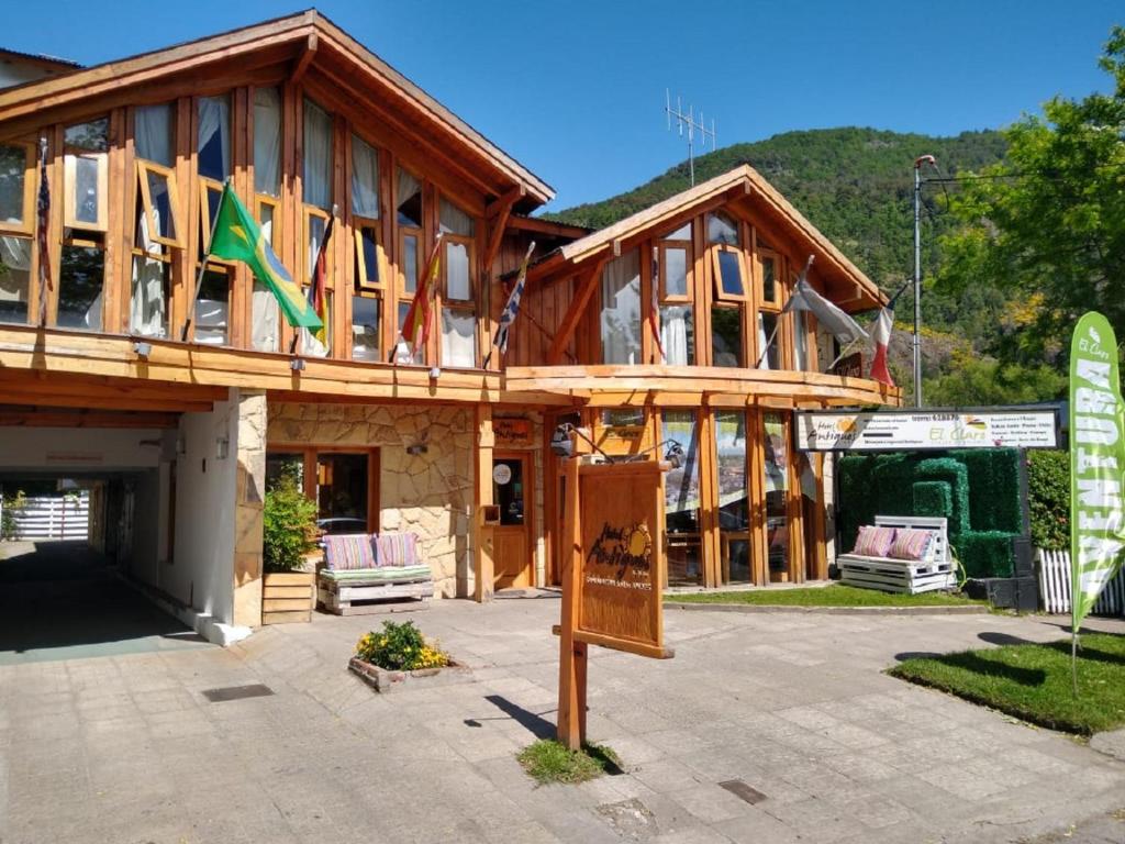 een groot houten huis met een bord ervoor bij Hotel Antiguos in San Martín de los Andes