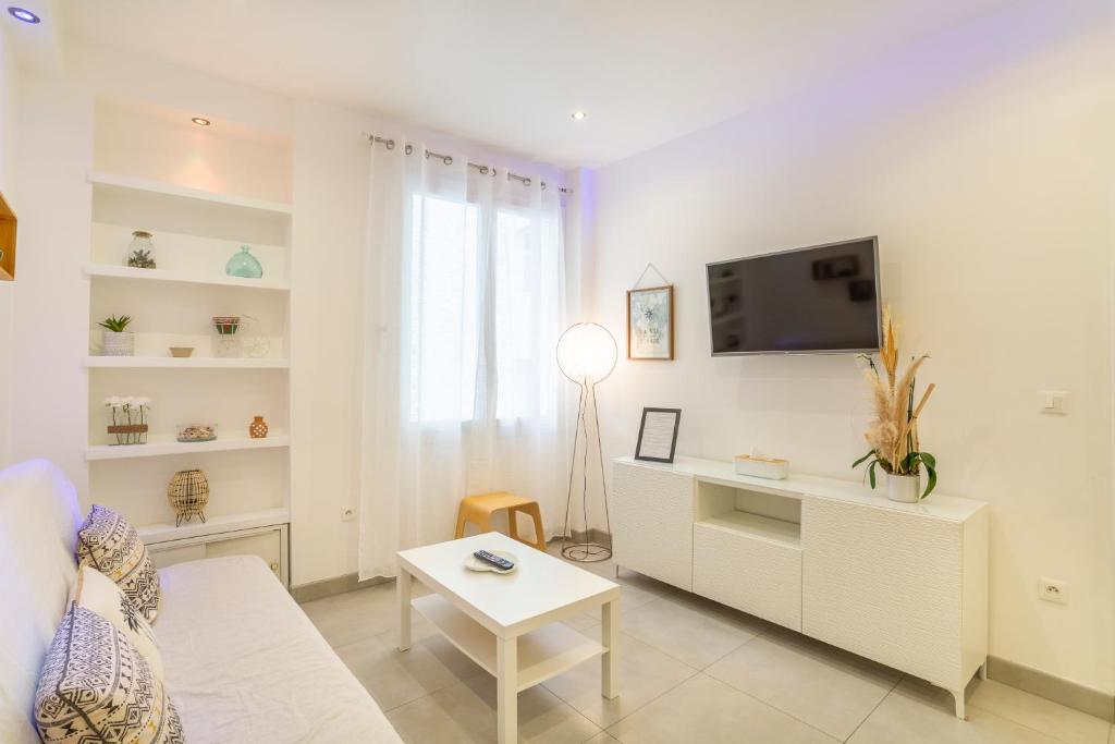 een woonkamer met een bank, een tv en een tafel bij Appartement "Les pieds dans l'eau" 1 chambre Parking JO in Marseille