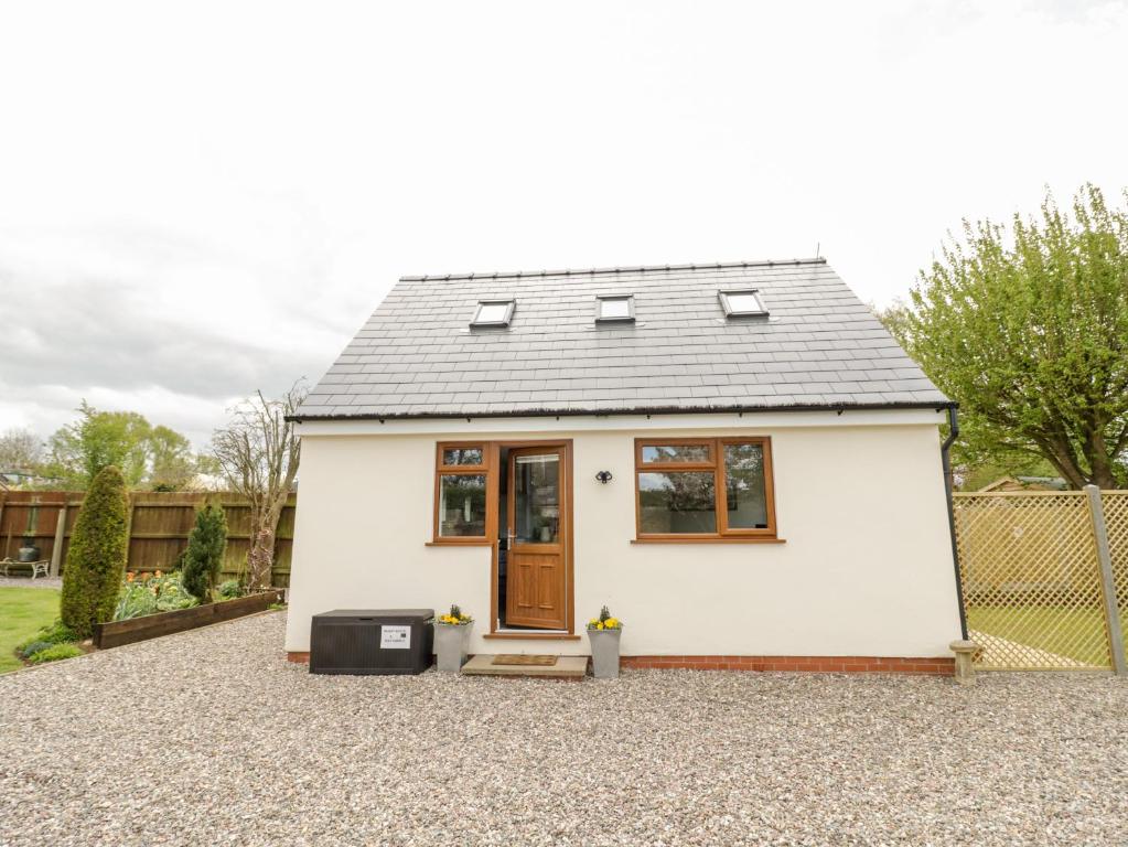 a small white house with a brown door at Meadow Cottage in Broadway