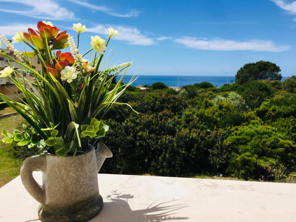 een vaas gevuld met bloemen zittend op een tafel bij Voce Del Mare - sea view- Alghero Airport in Alghero