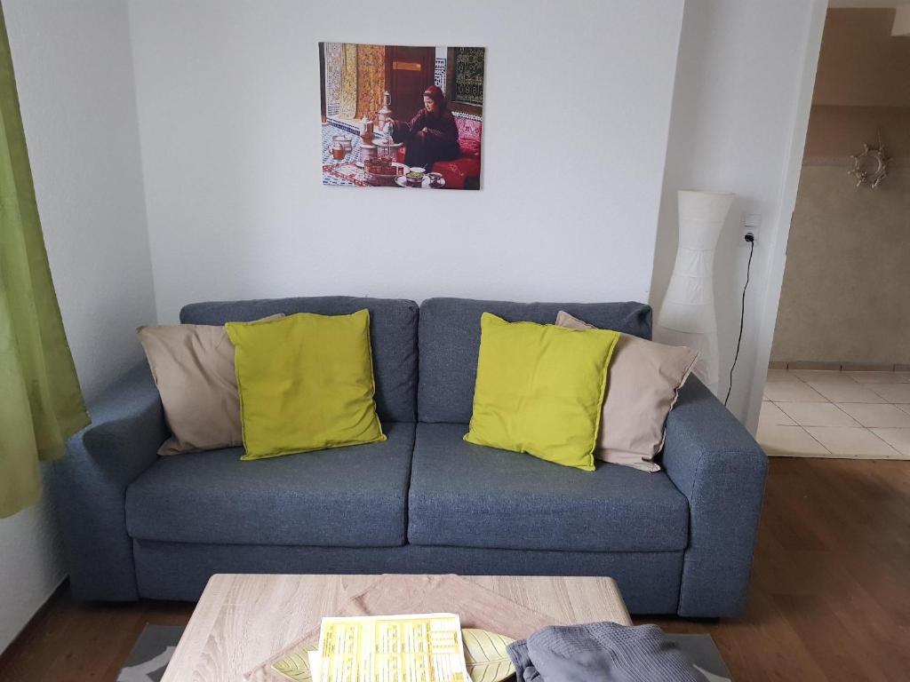 ein blaues Sofa mit gelben Kissen im Wohnzimmer in der Unterkunft Haus Marrakesch in Borkum