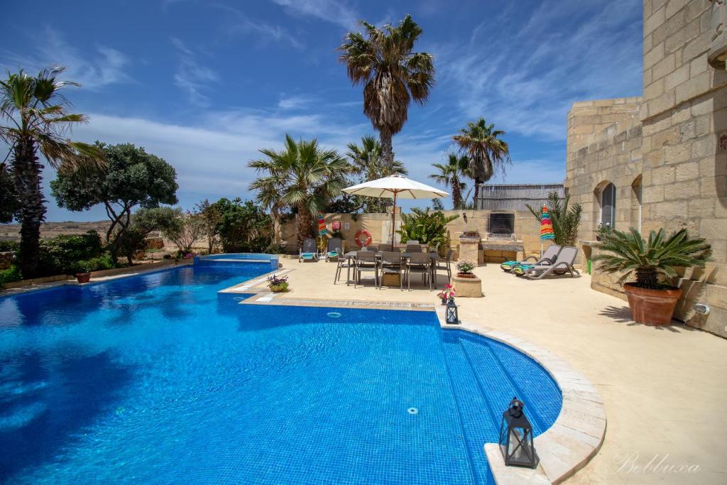 uma grande piscina azul ao lado de um resort em Bebbuxa Holiday Home em Għarb