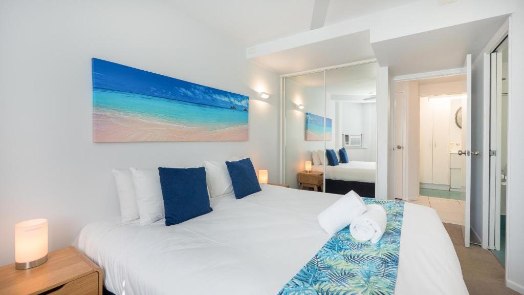 una camera da letto con un grande letto bianco con cuscini blu di Aegean Mooloolaba a Mooloolaba